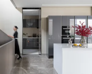 A modern kitchen with a glass countertop, featuring stainless steel appliances, a white island, and red berries in a vase.