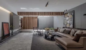 A modern living room with concrete walls, a brown leather sofa, and a sleek coffee table.
