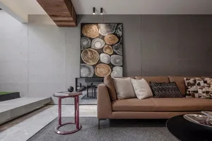 A modern living room featuring a concrete wall, metal ceiling beam, leather sofa, and canvas artwork.