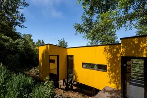 A bright yellow modern house with metal siding.