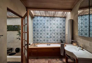 Industrial-style bathroom with blue patterned tiles, wooden accents, and a freestanding bathtub.