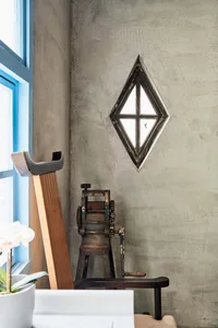 An industrial-style interior design featuring a concrete window frame, with a vintage metal stool and a wooden board in the f