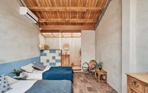Modern, minimalist bedroom with concrete walls and wooden ceiling beams.