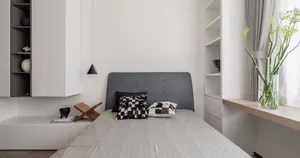 Minimalist bedroom featuring concrete bed frame and gray pillows.