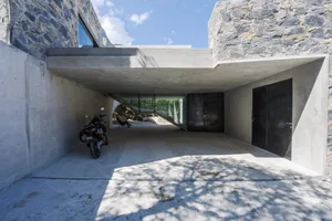 Concrete and stone exterior of a minimalist architectural building, featuring a covered walkway.