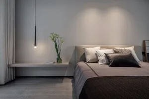 Bedroom with minimalist design, grey textiles, and wooden flooring.