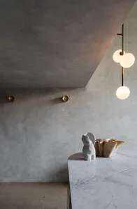 A minimalist living room with concrete walls, marble table, and abstract sculptures.