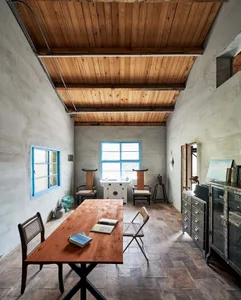 A minimalist living room with wooden furniture, including a wooden table, chairs, and a cabinet.