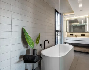 A modern bathroom featuring a freestanding concrete bathtub, black fixtures, and minimalist design.