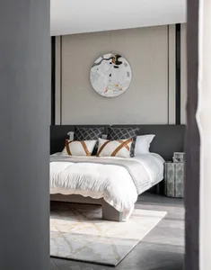 Modern bedroom featuring a bed with a fabric headboard, metallic nightstand, and abstract wall art.