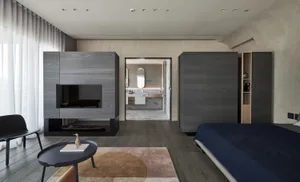 A modern bedroom suite featuring minimalist furniture and a large, dark-colored cabinet.