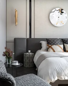 A modern bedroom featuring a textured leather headboard, white bed linen, and decorative cushions.