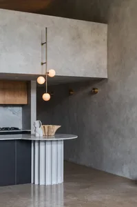 A modern kitchen featuring metallic pendant lighting and a sculptural centerpiece.