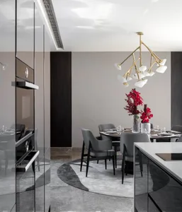 Modern dining room featuring a black glass table, metal chairs, and floral arrangements.