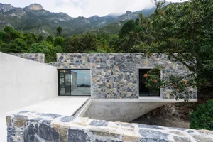 Modern exterior of a mountain residence featuring stone and concrete materials.