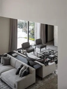 A modern grey living room with a comfortable sectional sofa adorned with dark grey cushions and decorative pillows, accompani