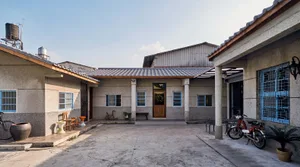 Modern house with a concrete exterior, featuring a spacious courtyard with furniture and a bicycle.
