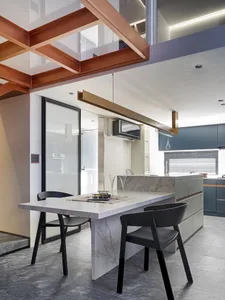 A modern kitchen featuring a white marble countertop and black chairs.