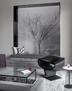 A modern living room featuring a glass window with a minimalist tree and rock garden