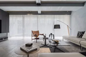A modern minimalist living room with contemporary furniture, white walls, and a large window.