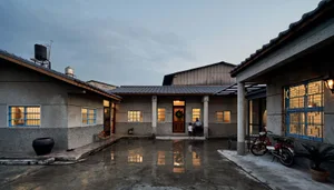 Concrete exterior of a modern residential home with a small courtyard and a single adult and child standing at the entrance.