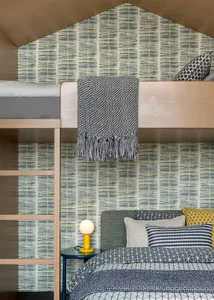 Modern bunk bed with a geometric floor pattern, wooden ladder, and plush bedding in a bedroom setting.