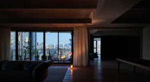 Modern living room with large glass windows overlooking a cityscape at dusk.