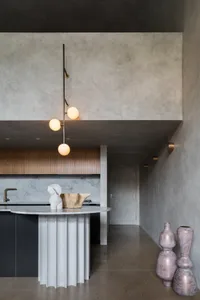 A modern residential kitchen featuring a marble countertop and concrete elements.
