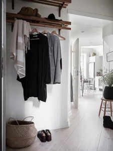 A minimalist hallway with wooden clothes hangers holding black attire.