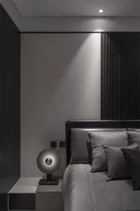 Bedroom with minimalist design featuring grey textured fabric bedding and wooden accents.