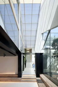 Modern kitchen interior with glass walls, metal accents, and concrete flooring.
