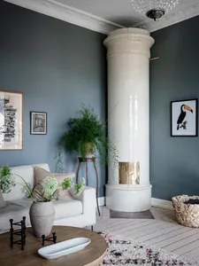 A modern living room featuring white tiled columns, a white sofa, potted plant, and decorative rug.
