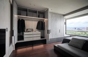 Modern minimalist bedroom with concrete cabinets and a large window overlooking a cityscape.