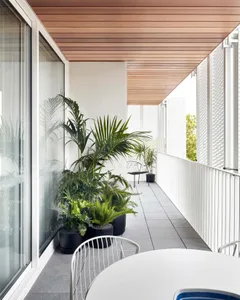 A modern balcony featuring sleek furniture, plants, and a minimalistic ceiling design, providing a relaxing outdoor living sp