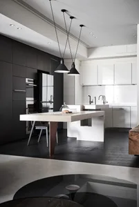 A modern kitchen featuring a concrete island with pendant lights hanging overhead and a sleek, minimalist design.