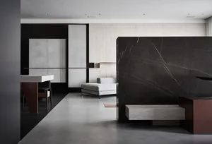 Modern living room with grey concrete walls, a black marble partition, and a grey sectional sofa.