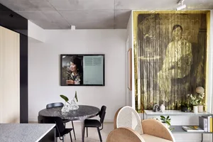 A modern dining room featuring a metallic wall screen and a round table with black chairs.