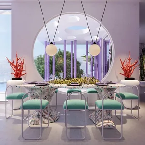 Modern dining room featuring a table with a terrazzo top and turquoise chairs arranged around it, with red coral sculptures o