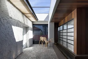 A modern interior space with concrete walls and floor, featuring a wooden deer statue and a glass wall.