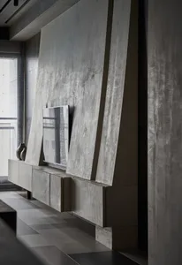 A modern living room with concrete walls, a floating entertainment center, and a large screen TV.