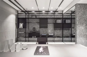 A clean, modern office space featuring concrete-textured walls, minimalist furniture, and a glass desk.
