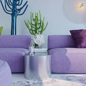A modern living room featuring a purple sofa, glass side table, and metallic plant sculptures.