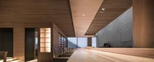 A sleek, modern restaurant bar with wooden accents, minimal lighting, and a spacious seating area.