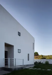 A modern residential exterior with a plain white concrete wall and small windows.