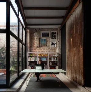 A modern workspace featuring industrial elements such as brick walls, glass surfaces, and wooden accents.