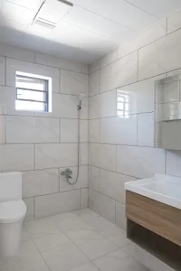 Modern minimalist bathroom featuring marble tiles and a floating wooden vanity.