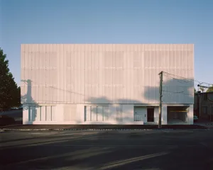 A modern building facade with white perforated panels and minimal windows.