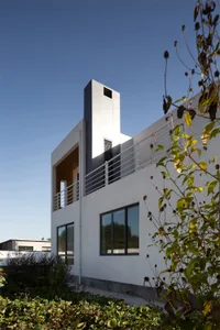 Modern design residential home with concrete facade, glass windows, and metal railings.