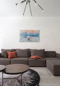 Modern living room featuring a grey sectional sofa, coffee table, and colorful artwork on a white brick wall.