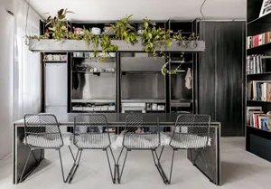 Modern urban housing unit with metal finishes, featuring a dining area with black metal chairs and table, and a kitchenette w